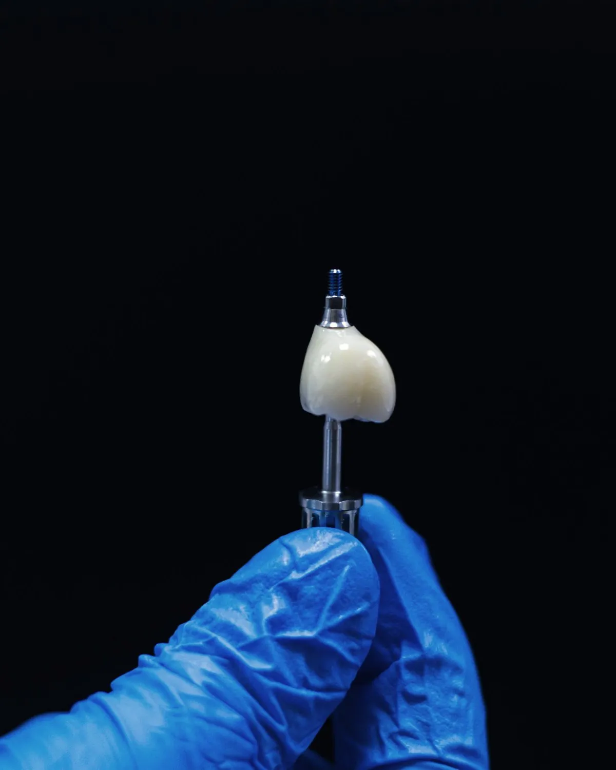 A finished zirconia crown held in the hand